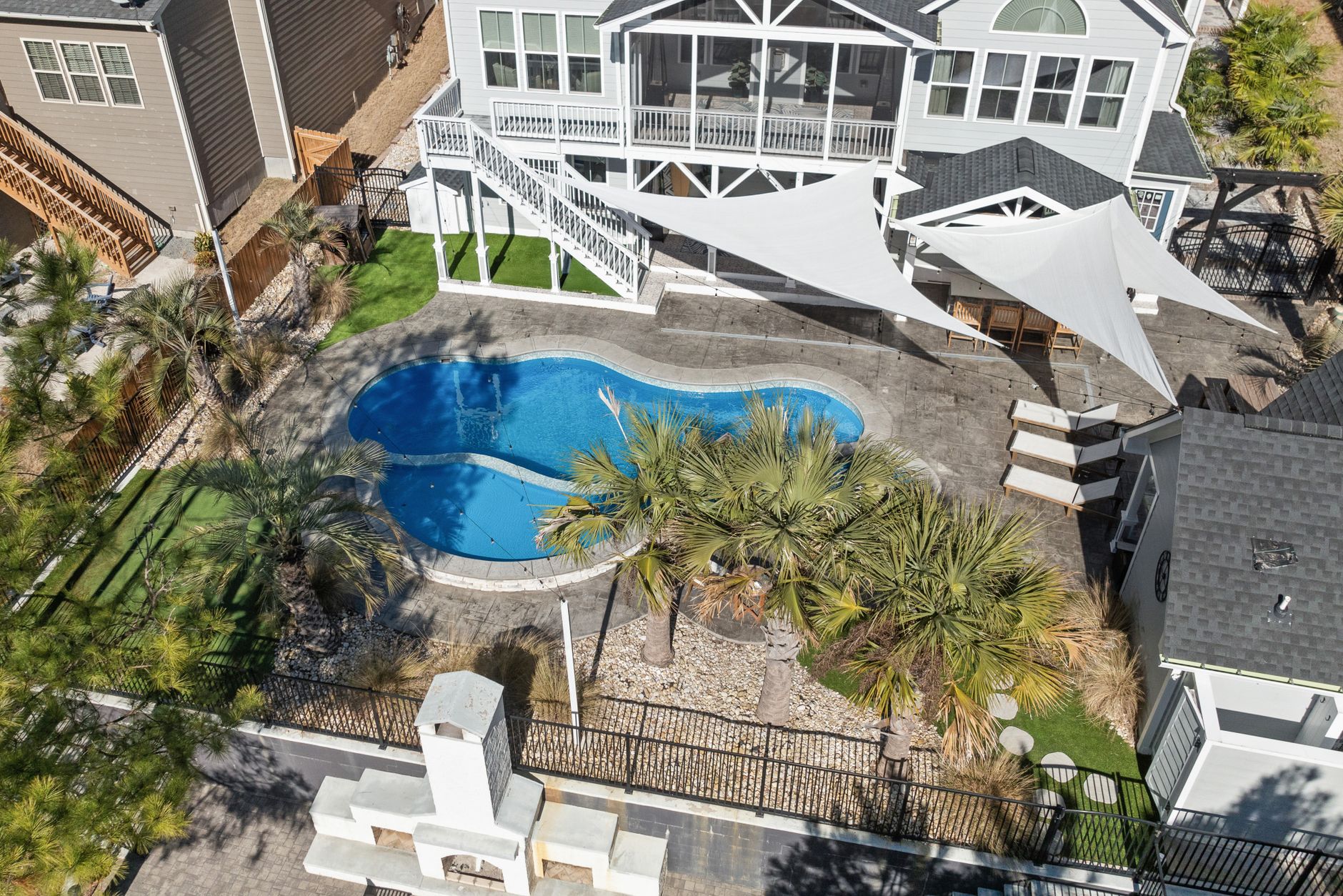 Aluminum picket fence enclosing a backyard swimming pool at a Florida home with palm trees