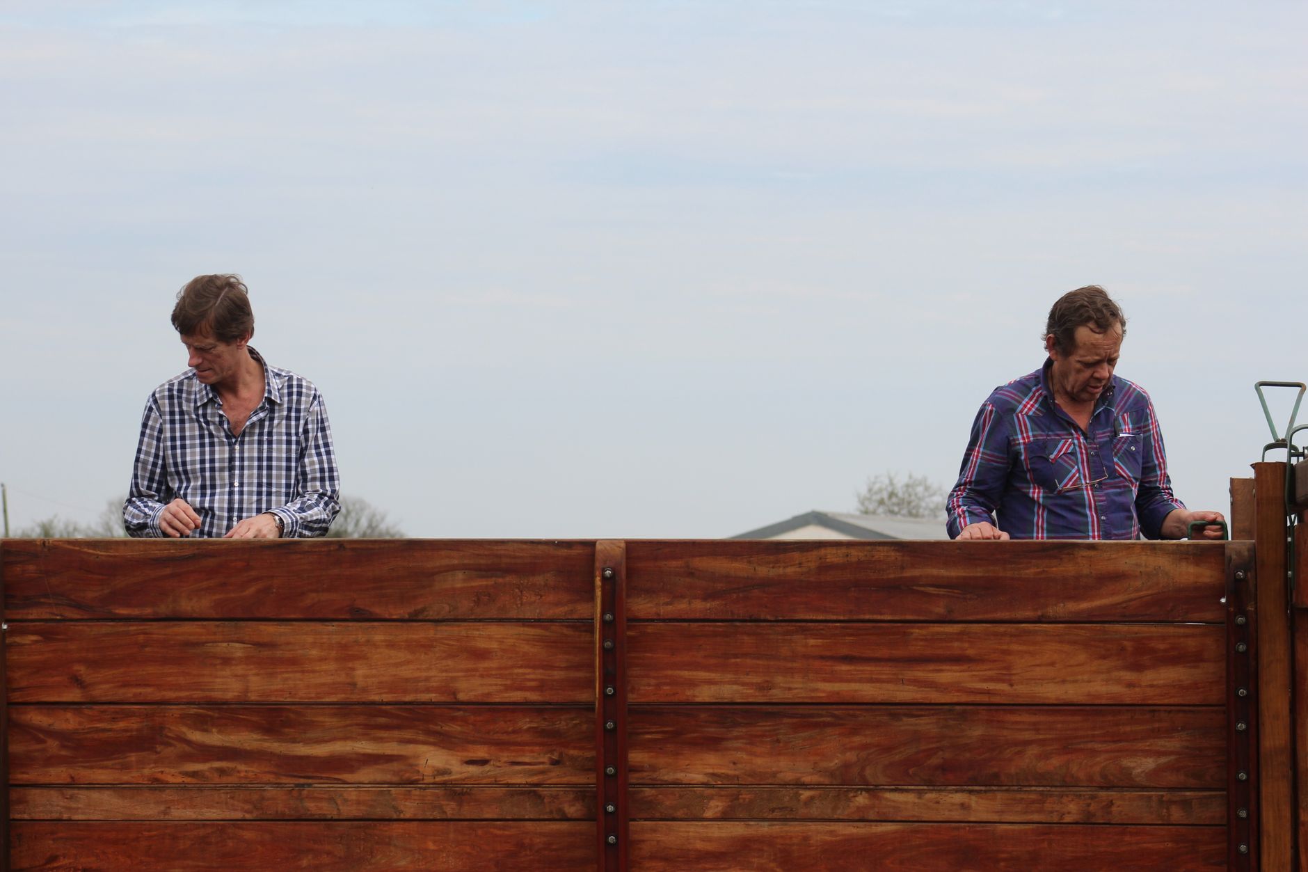 Two workers building a tall wooden fence