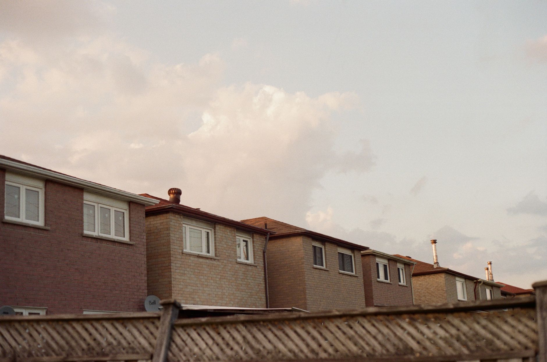 Wooden privacy fence in a residential neighborhood with storm clouds building overhead